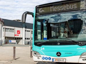 KMG-Bus steht seitlich, mit der Front zum Betrachter, neben dem Kärntner Messezentrum, in der Zielanzeige steht das Wort Messebus